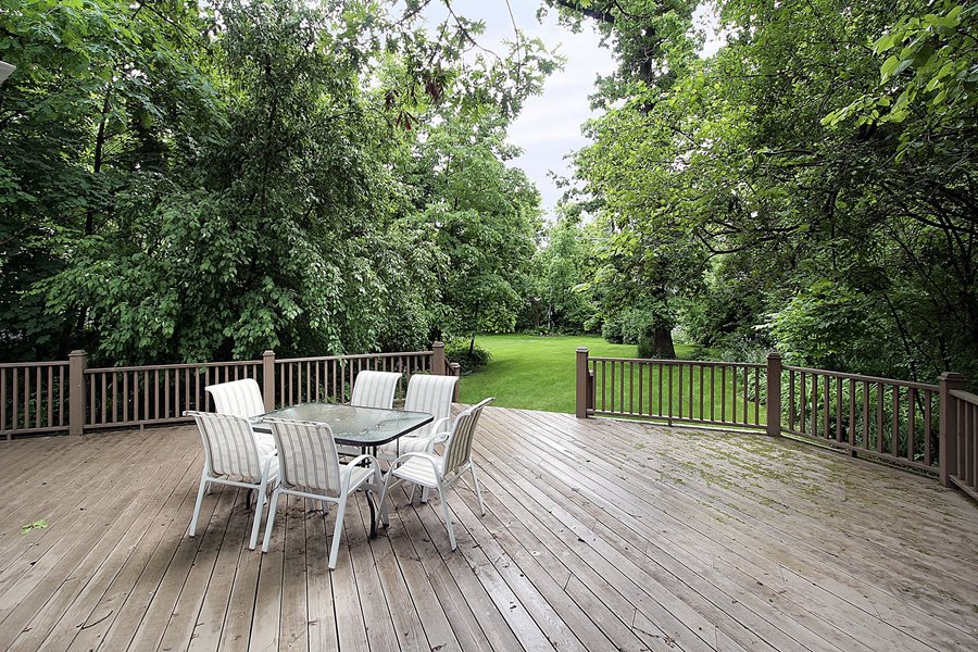Spacious backyard wood deck surrounded by large trees and natural greenery.