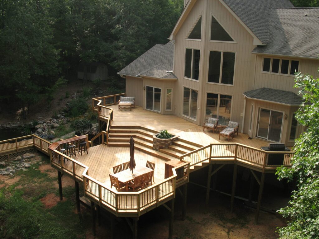 Backyard wood deck oasis with comfortable seating and green landscaping.