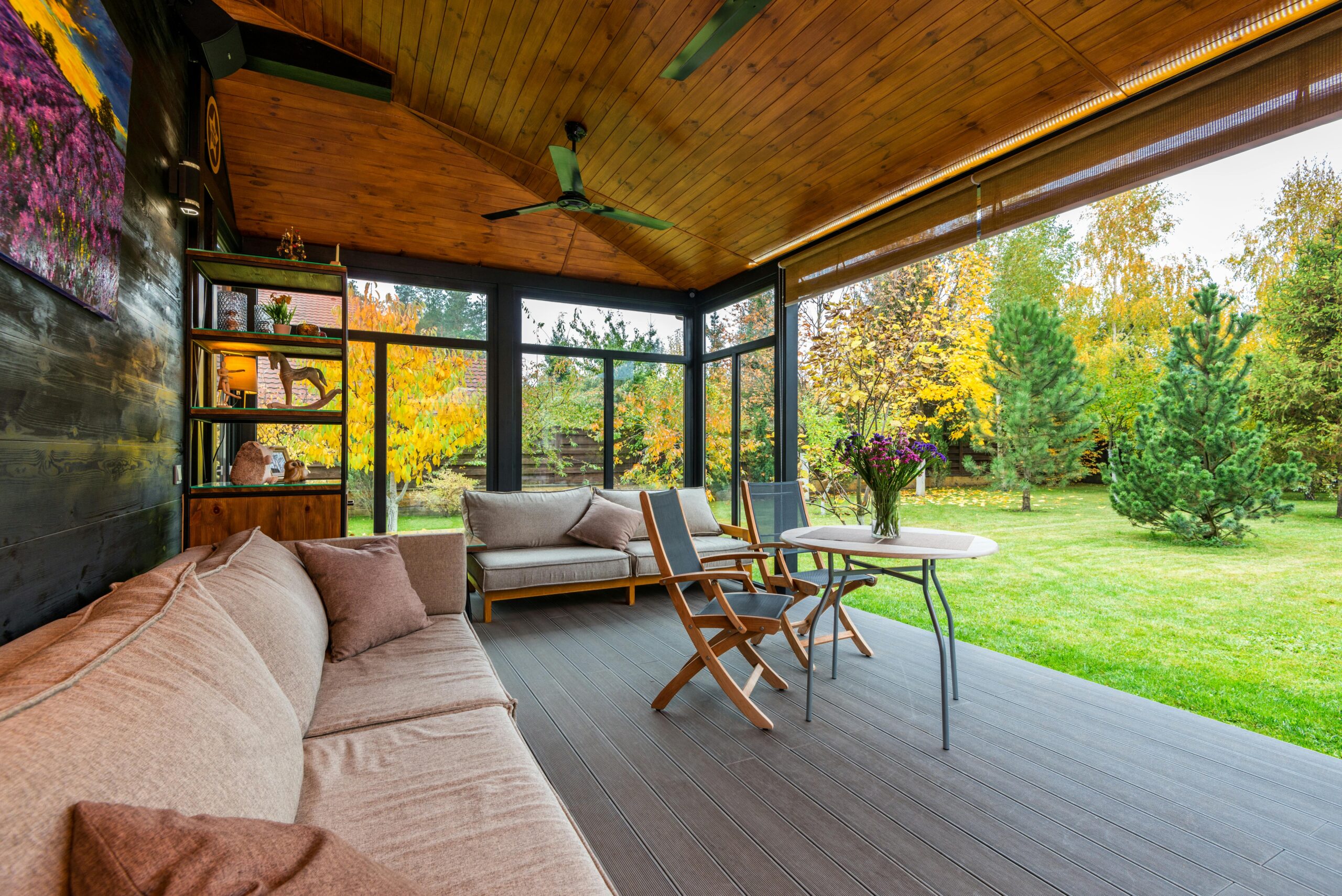 Covered deck with comfortable seating and a beautiful view of the backyard, designed by trusted garage and deck specialists.