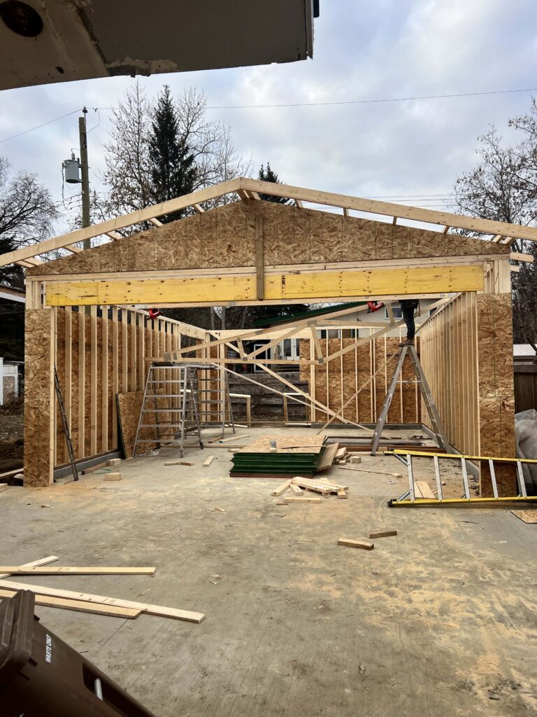 A garage under construction, featuring wood framing and roof trusses, built by Alberta Builder Services.