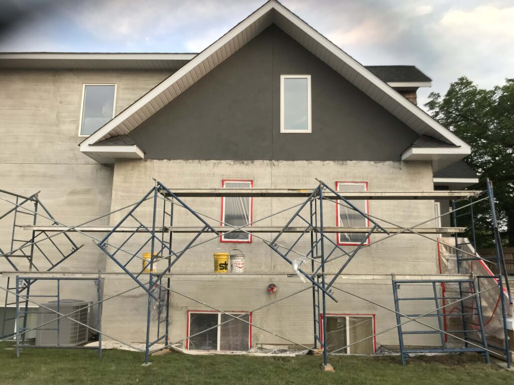 A modern two-story home featuring a sleek grey stucco exterior with clean white window trims, showcasing Alberta Builder Services' expertise.