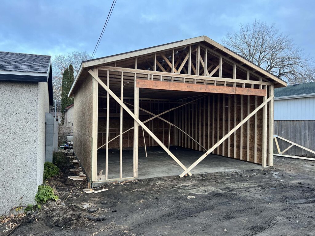 A partially constructed garage with a framed roof and wooden structure, built by Alberta Builder Services.