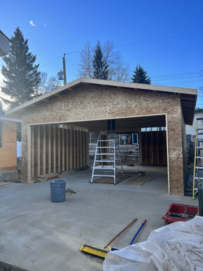 A partially completed garage with framed walls, roof, and a concrete foundation, built by Alberta Builder Services.