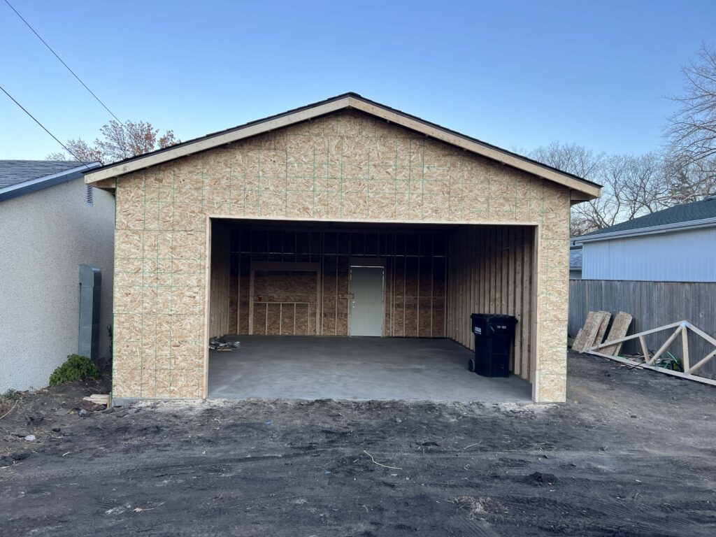 A newly constructed garage with framed walls, roof, and an open entryway, built by Alberta Builder Services.