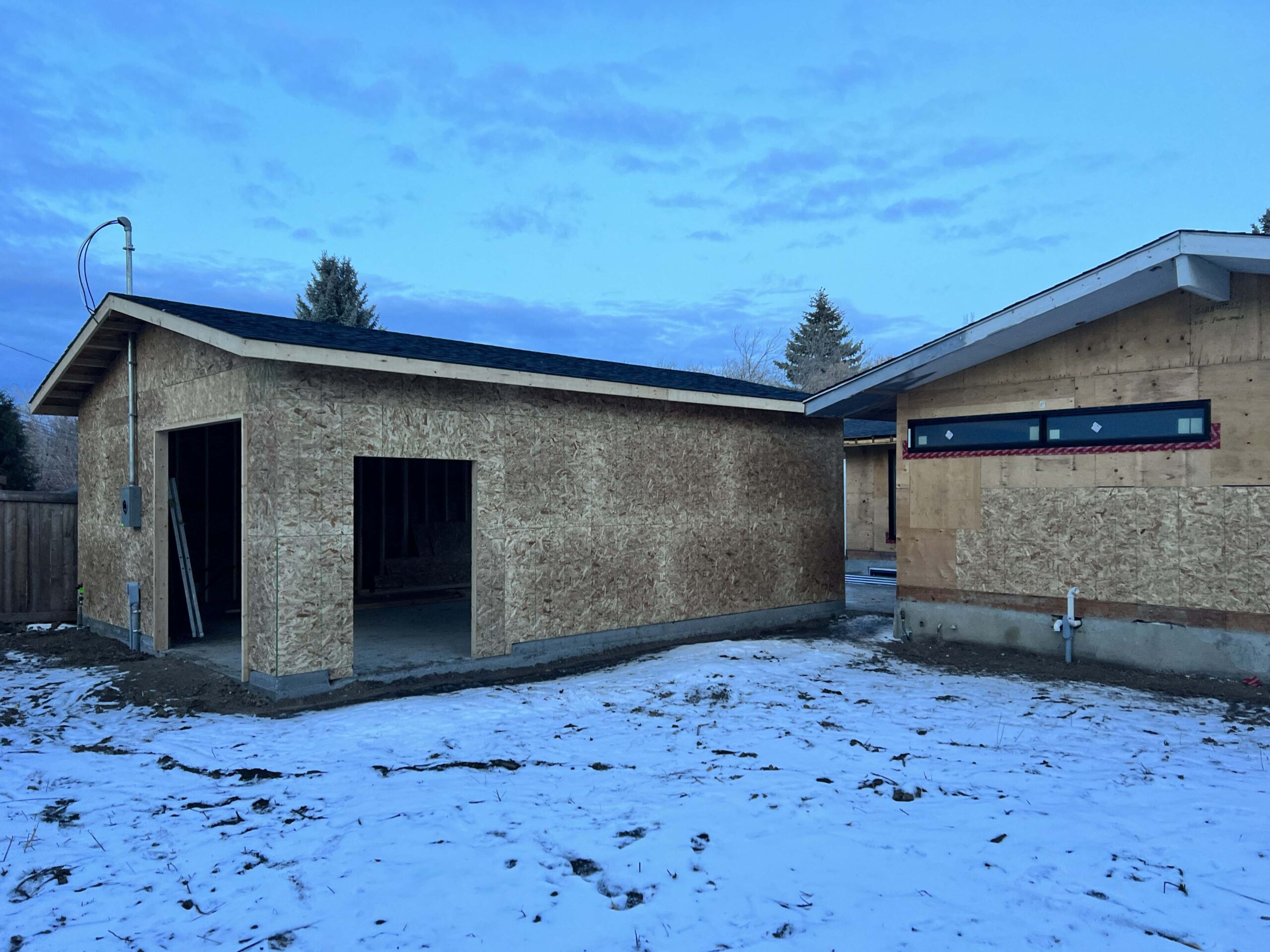 A newly framed detached garage with roof and door openings, built by Alberta Builder Services.