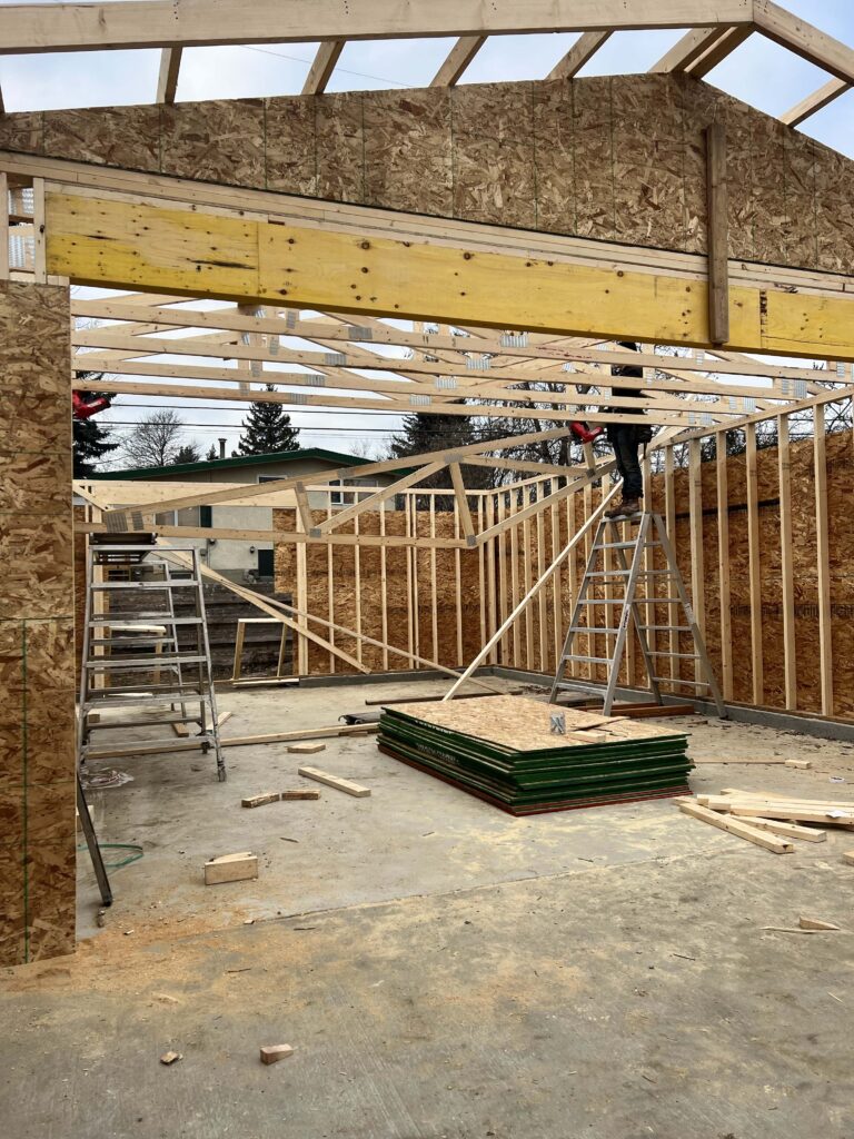 Framing work in progress for a custom garage with wooden beams and construction materials.