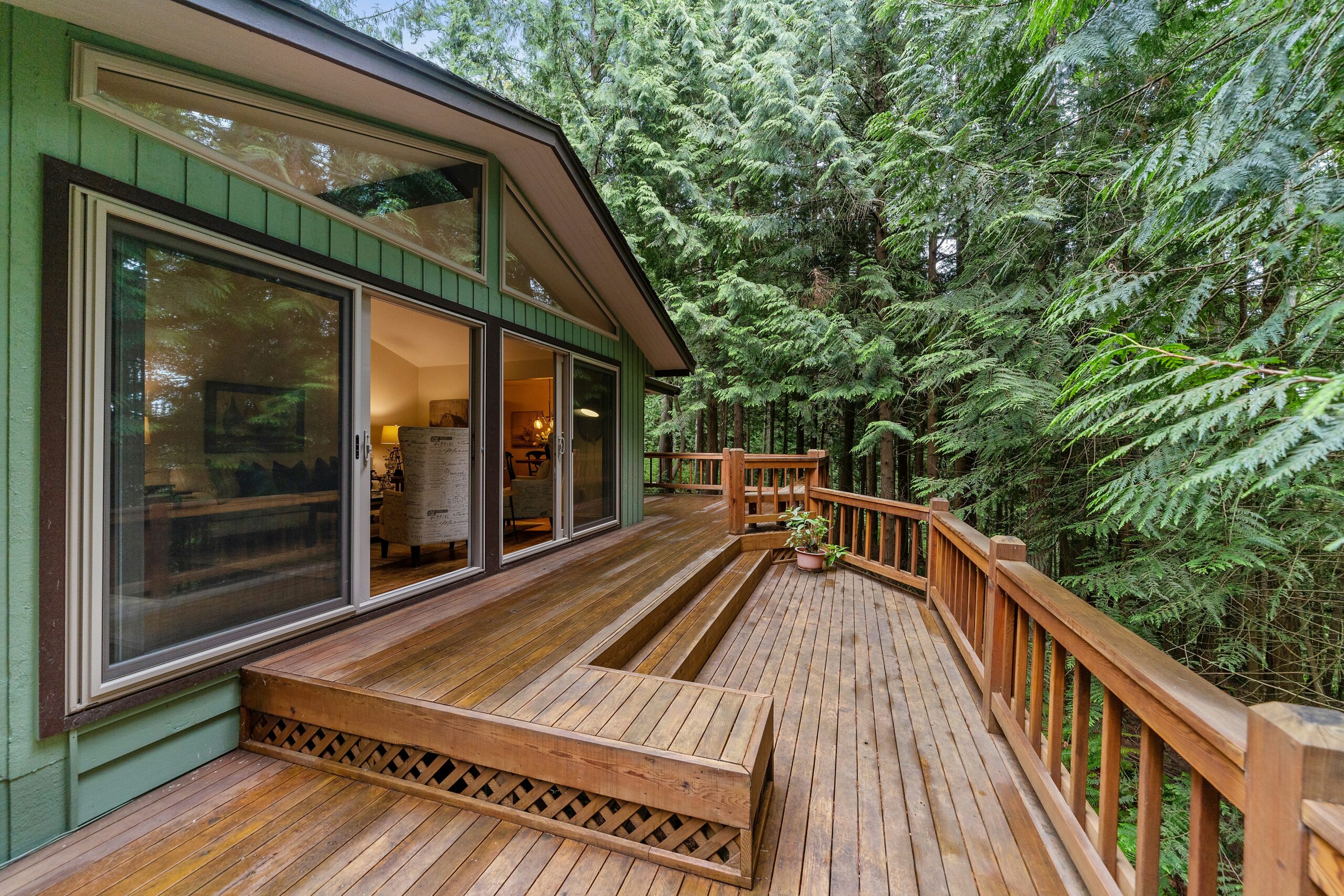 A spacious wooden deck with built-in seating, surrounded by lush greenery, showcasing Alberta Builder Services' craftsmanship for custom decks.