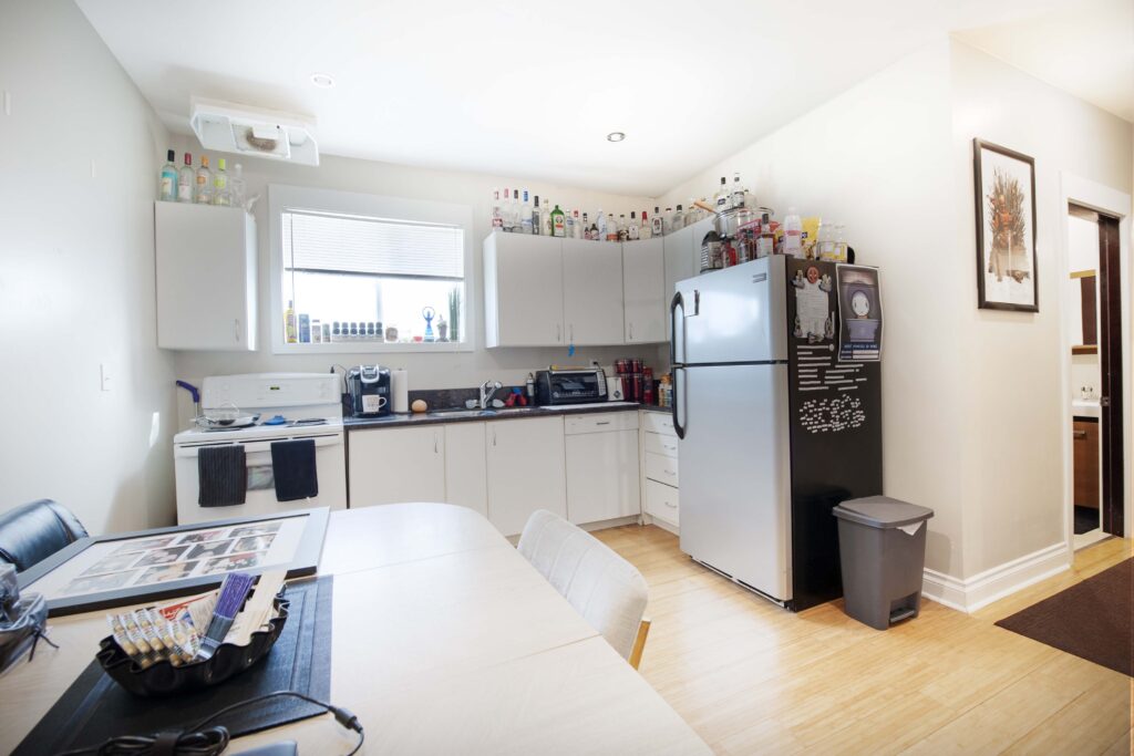 Modern renovated basement suite kitchen with white cabinetry and bamboo flooring.