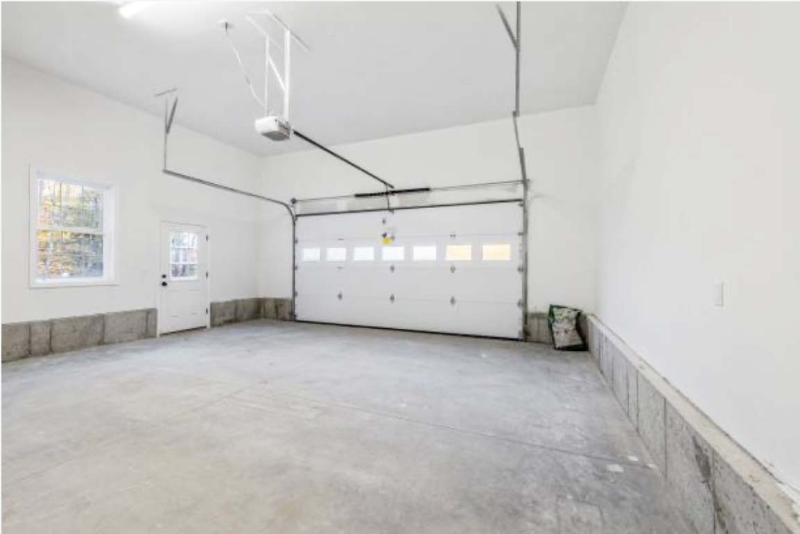 Spacious interior of a garage with clean floors, windows, and a large garage door, by trusted garage and deck building specialists.