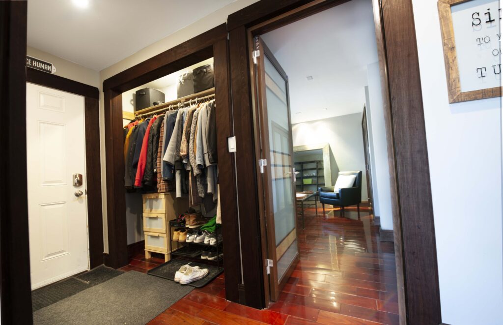 Modern back entrance with built-in closet, dark wood finishes, and polished hardwood flooring.