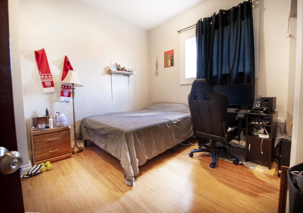 Renovated basement suite bedroom featuring a cozy setup with a bed, desk, and hardwood flooring.