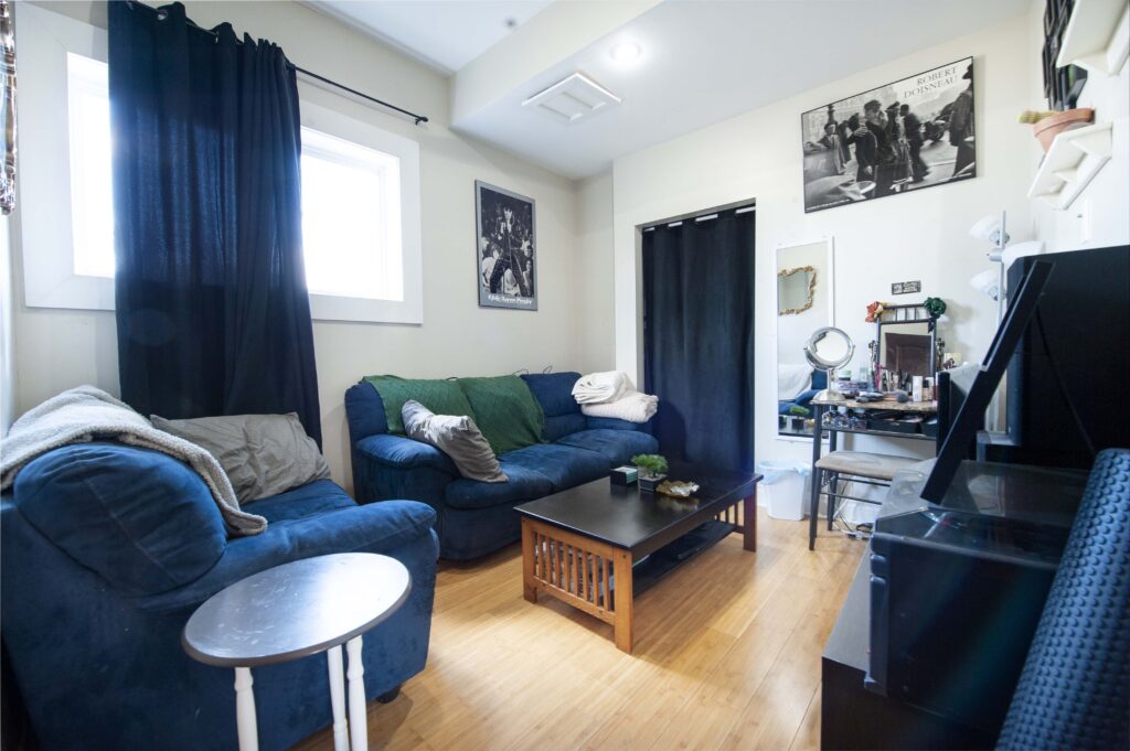 Basement suite den featuring cozy blue couches, a wooden coffee table, and personal decor.