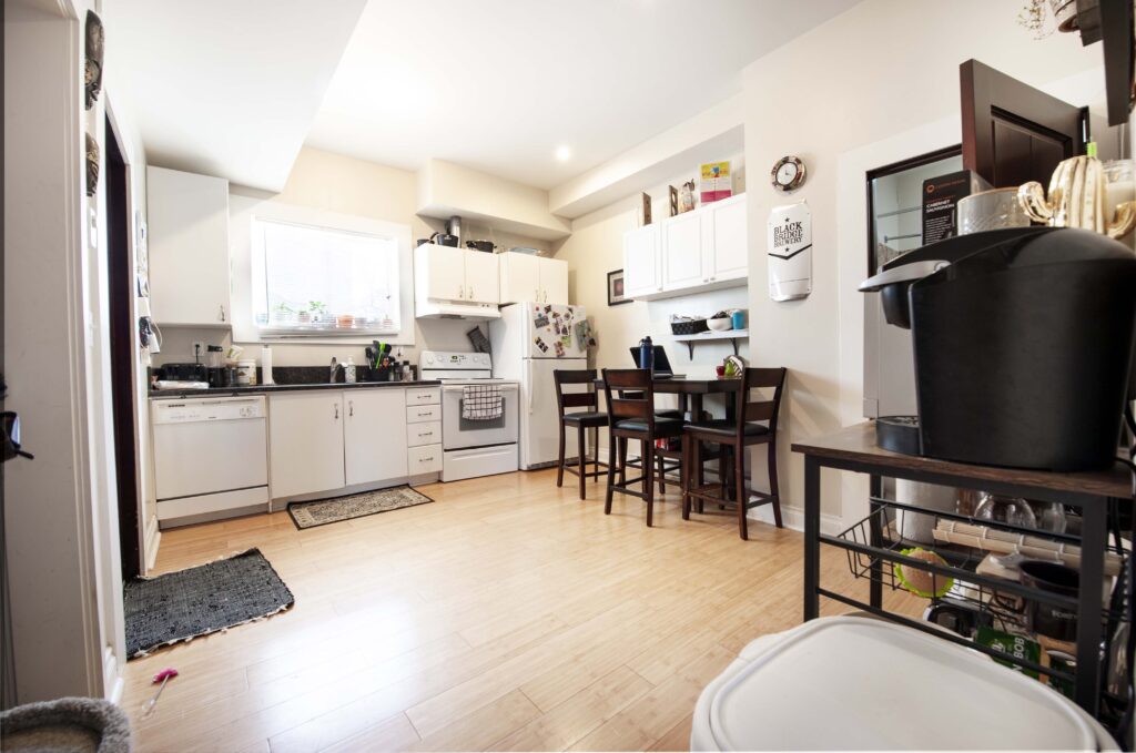 Modern basement suite kitchen and dining area with white cabinetry, bamboo flooring, and integrated dining space.