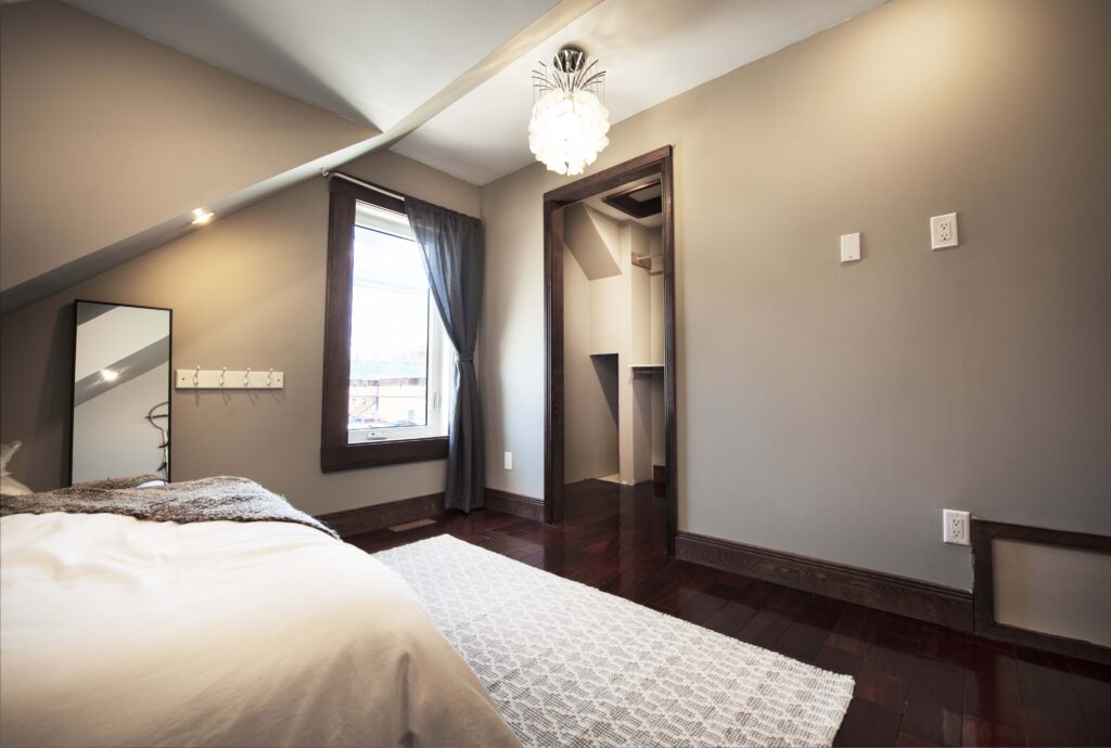 Renovated attic bedroom with natural light, a custom walk-in closet, and premium finishes by Alberta Builder Services.