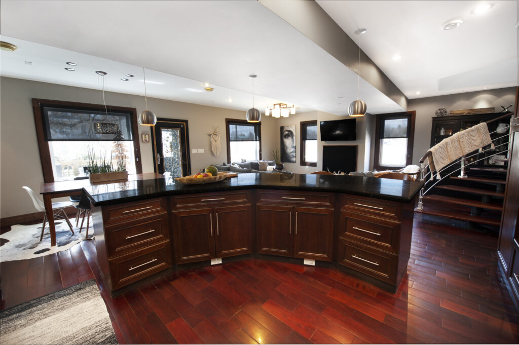 Modern kitchen with a large curved island and sleek dark cabinetry.