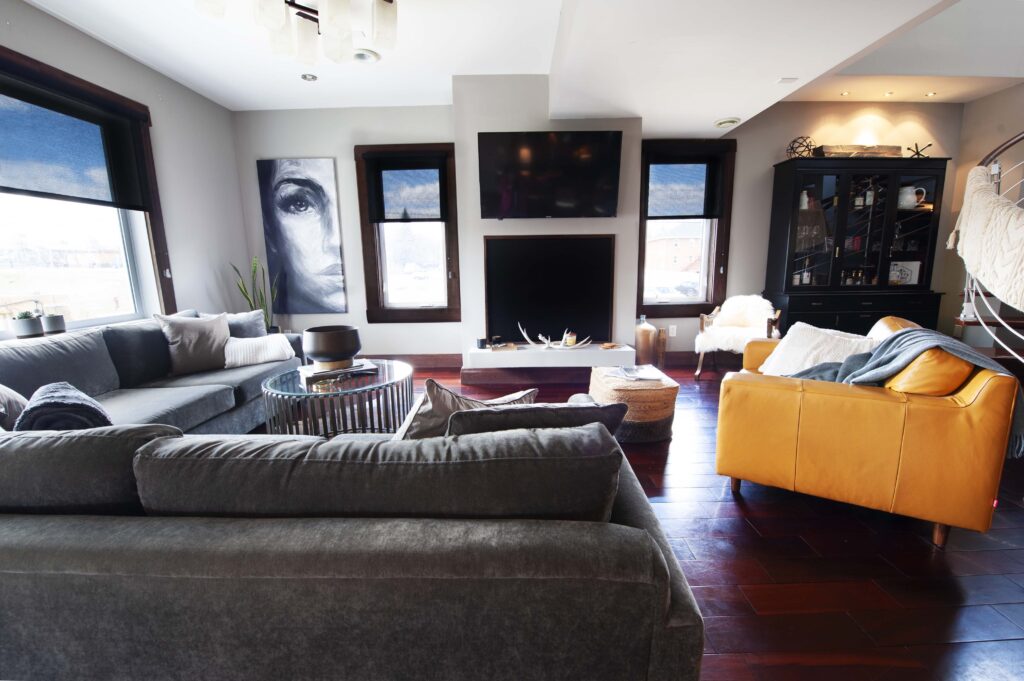 Modern living room with custom renovations, featuring sleek furniture, dark wood floors, and a built-in fireplace.