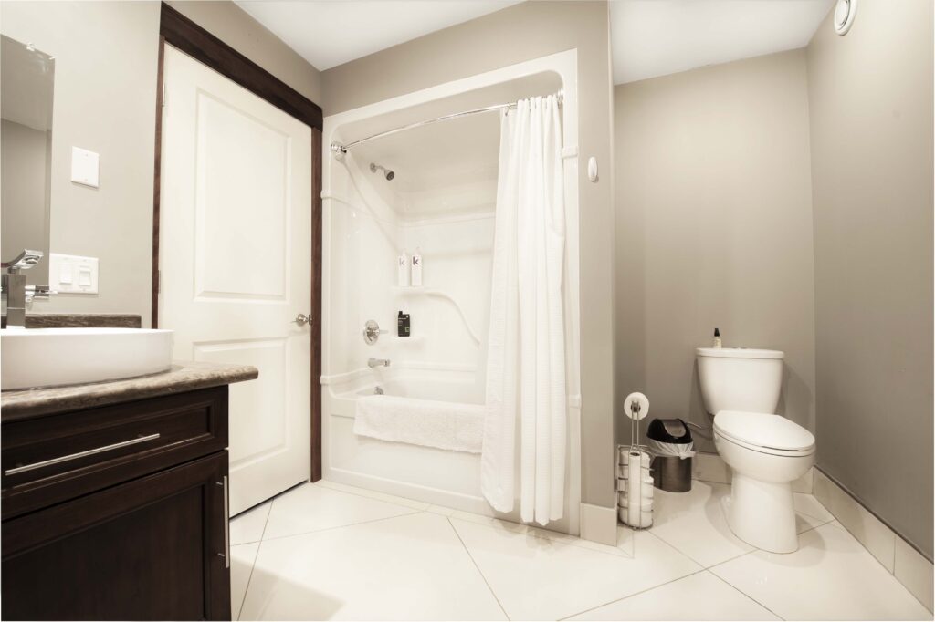 Modern bathroom with dark wood vanity, large tiles, and a shower-tub combo by Alberta Builder Services.