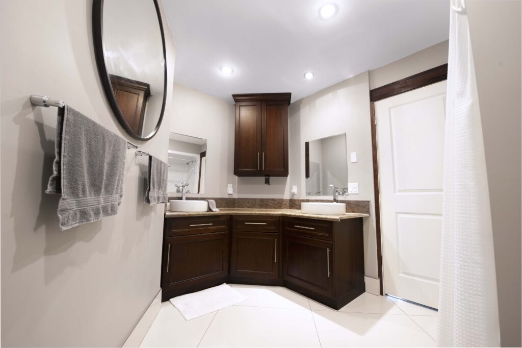 Elegant bathroom with dark wood cabinetry, dual sinks, and modern lighting by Alberta Builder Services.