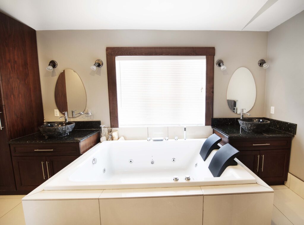 Elegant master bathroom with a jetted soaking tub and dark wood vanities featuring vessel sinks.