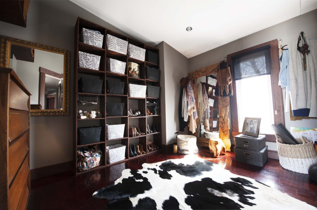 Custom master closet with built-in shelving, rustic mirror, and cowhide rug.