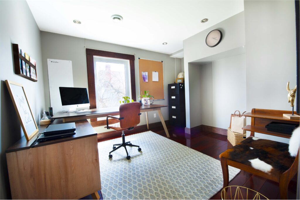 Modern home office with a wooden desk, corkboard, and natural light.