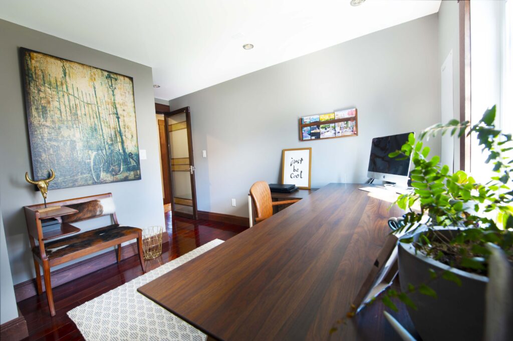 Stylish home office with wooden desk, vibrant artwork, and modern decor.