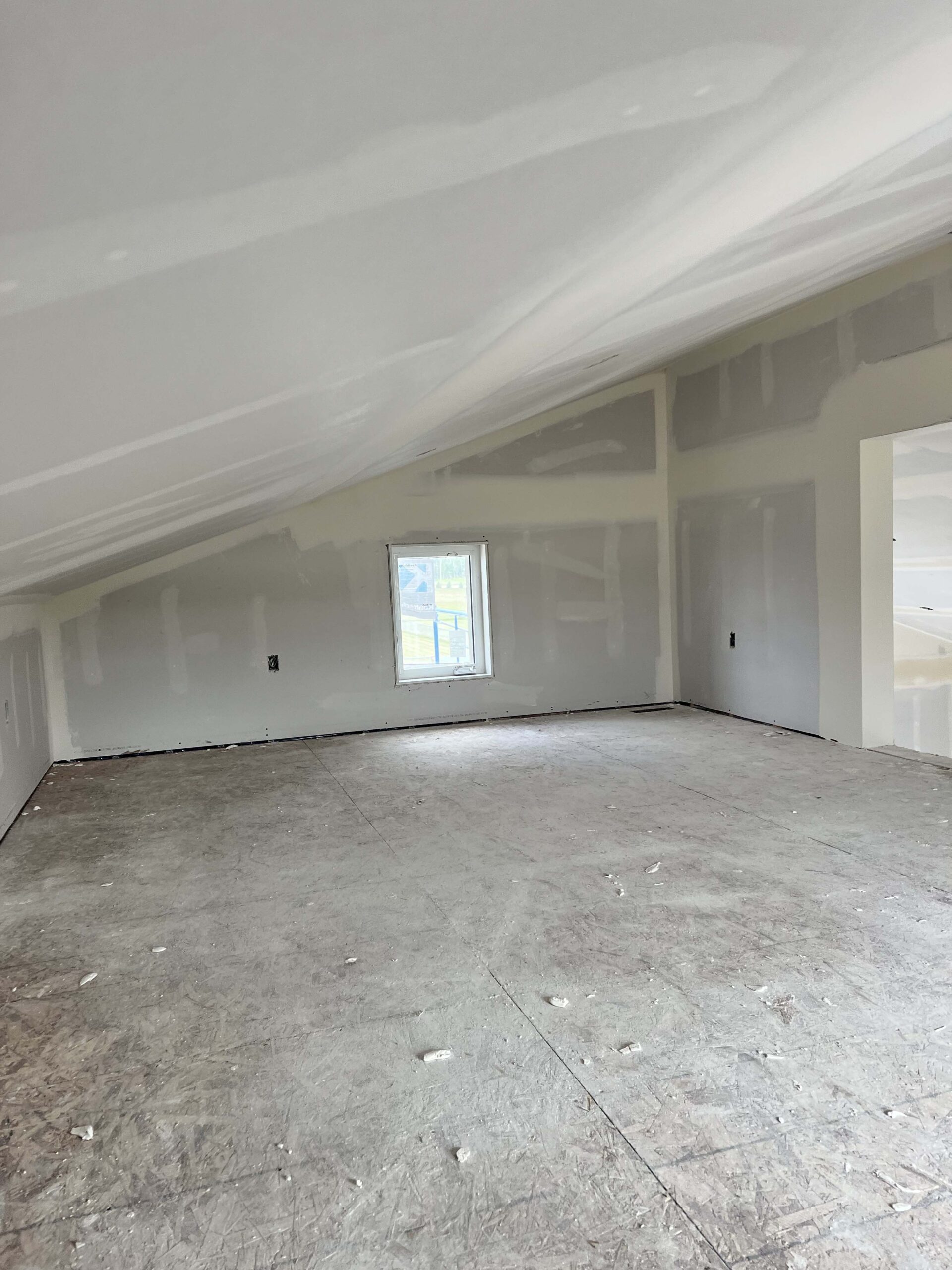 Spacious room with sloped ceilings and prepped drywall, highlighting Alberta Builder Services' quality in custom construction projects.