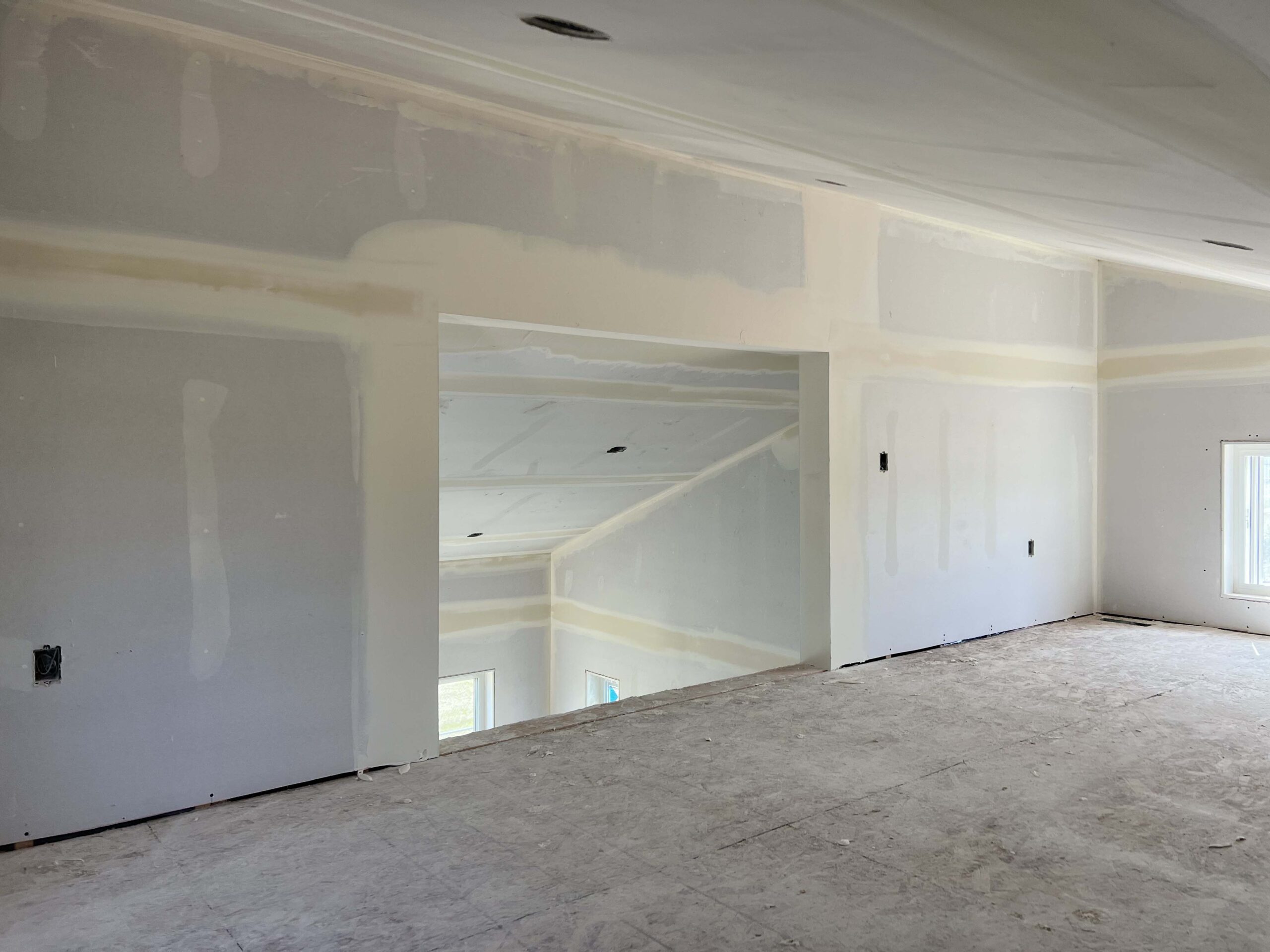 Partially finished residential room with smooth drywall, sloped ceilings, and window lighting, showcasing Alberta Builder Services' expertise in construction.