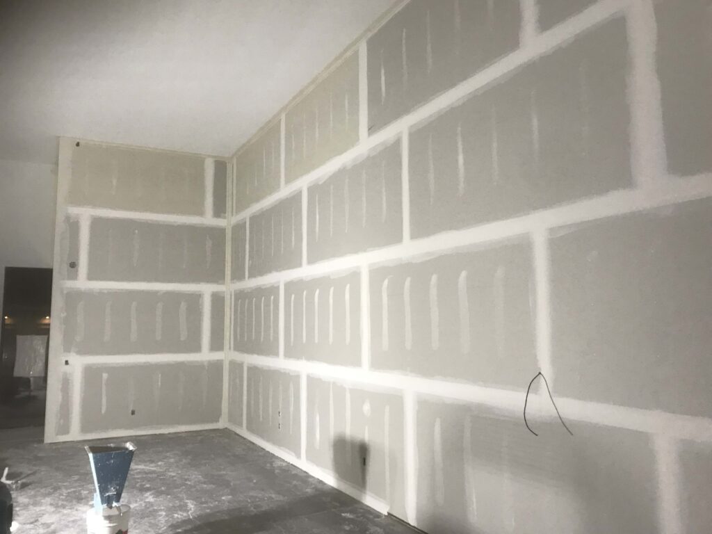 Interior commercial space with drywall installation complete and taped seams, showcasing Alberta Builder Services' construction expertise.