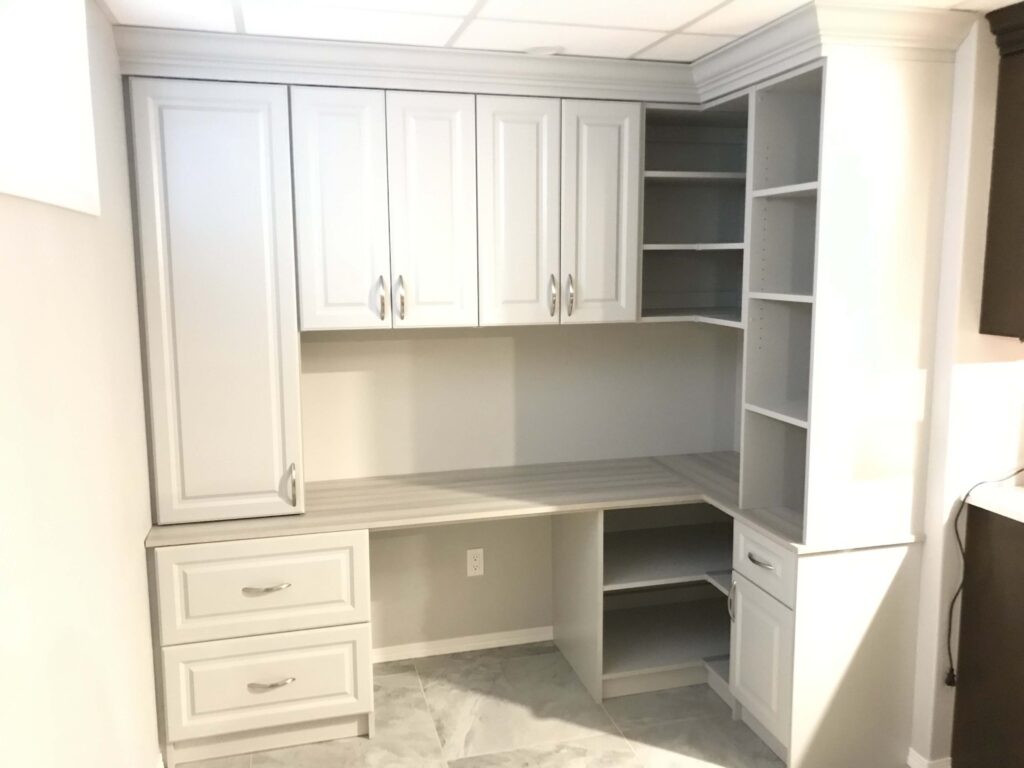 Custom-built white office cabinetry with ample storage, featuring cabinets, drawers, and open shelves, installed in a modern interior space.