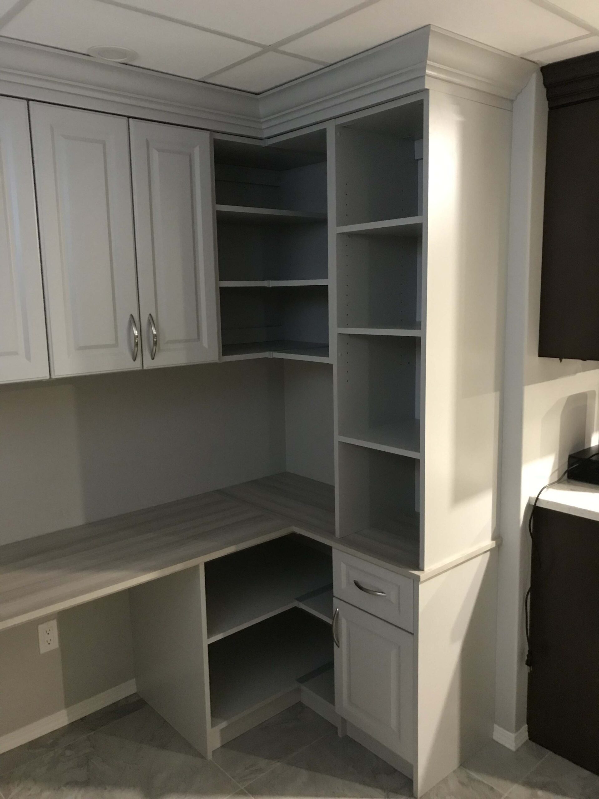 Custom-built corner office cabinetry with light grey finish, featuring ample storage, shelving, and workspace.