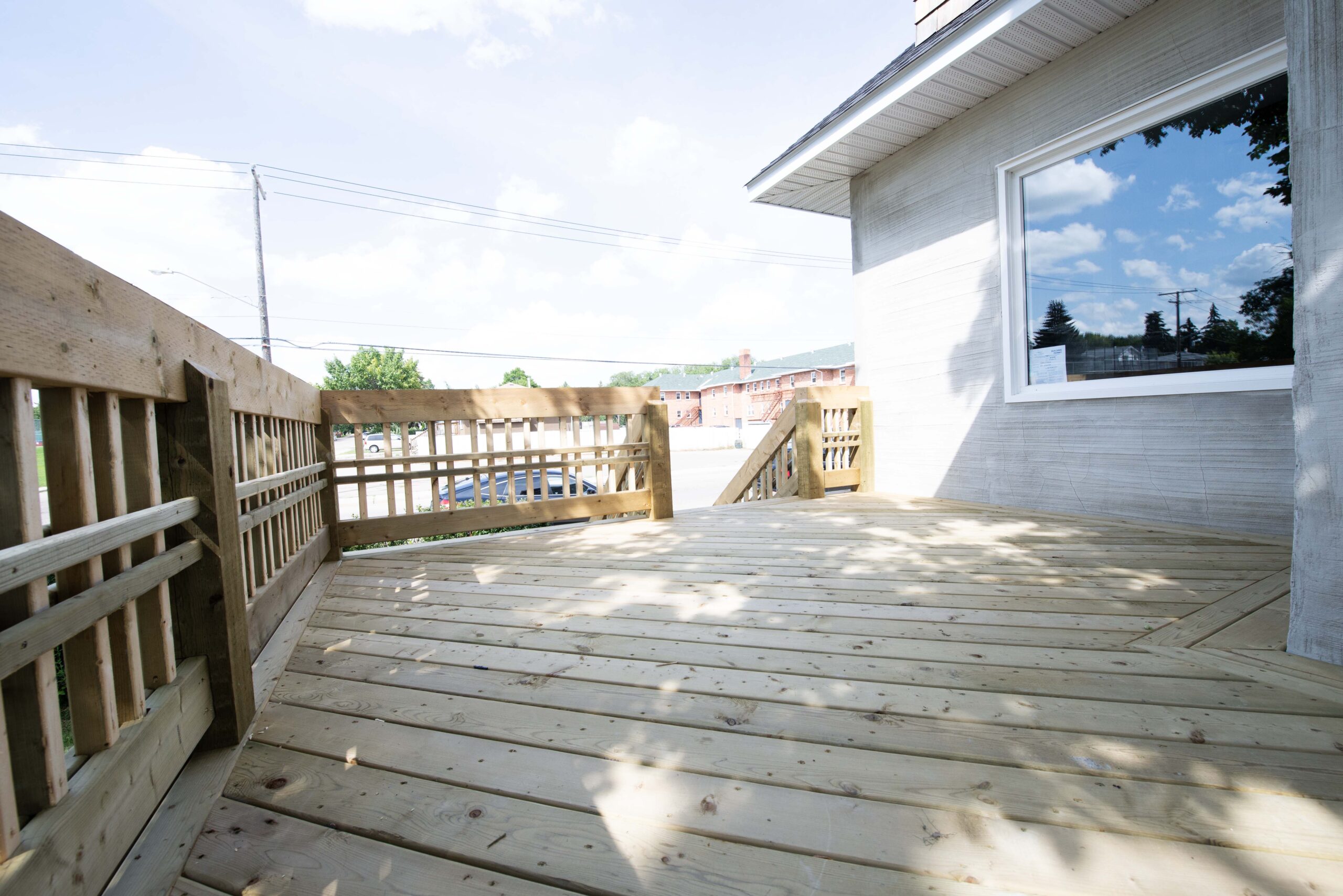 A newly constructed wooden deck with custom railings and stairs, showcasing Alberta Builder Services' craftsmanship.