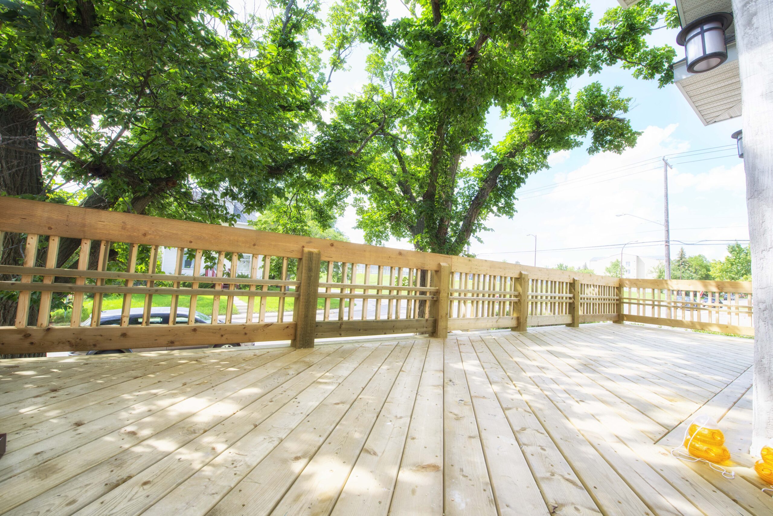 A spacious wooden deck with custom railings, surrounded by lush greenery, showcasing Alberta Builder Services' craftsmanship.