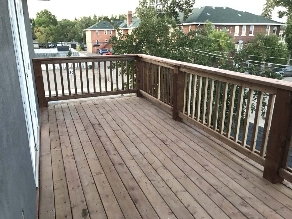 A completed wooden deck with custom railings, offering a spacious outdoor area, built by Alberta Builder Services.