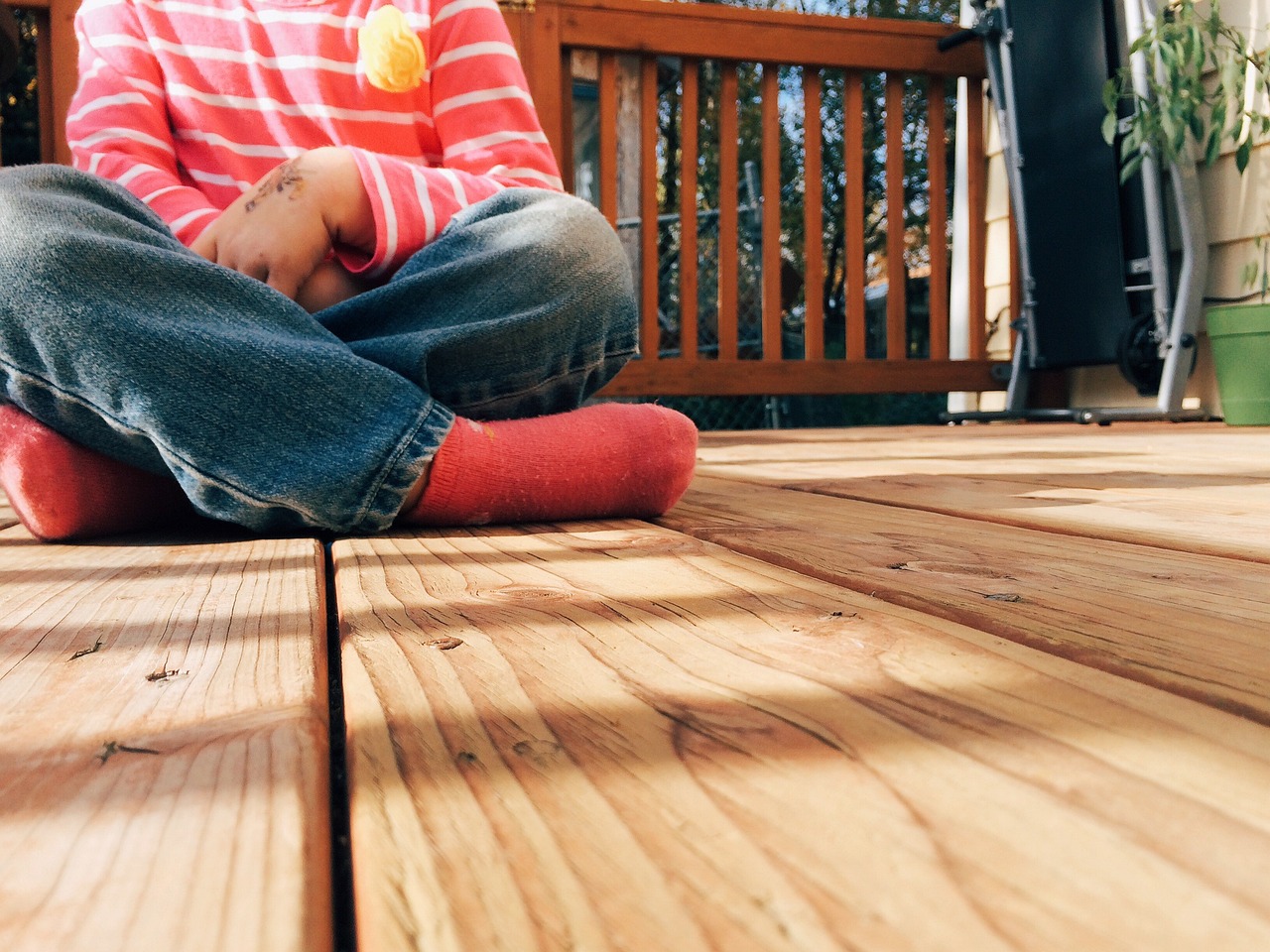 Child sitting on a wood deck, highlighting a safe and durable outdoor space.