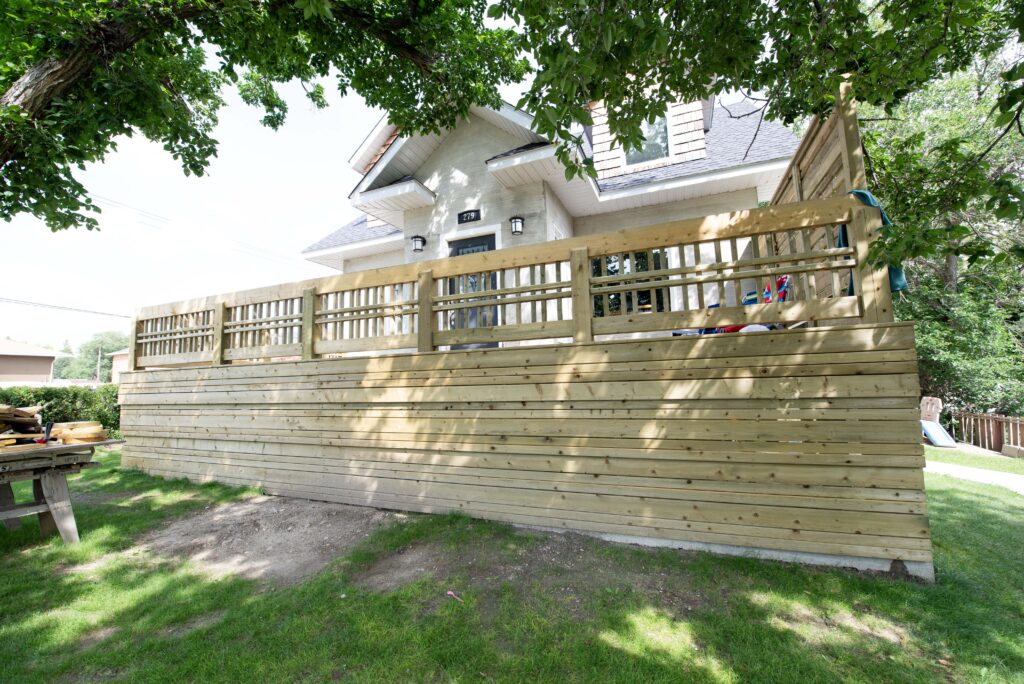 A large wooden deck with privacy railings and solid side paneling, constructed by Alberta Builder Services.