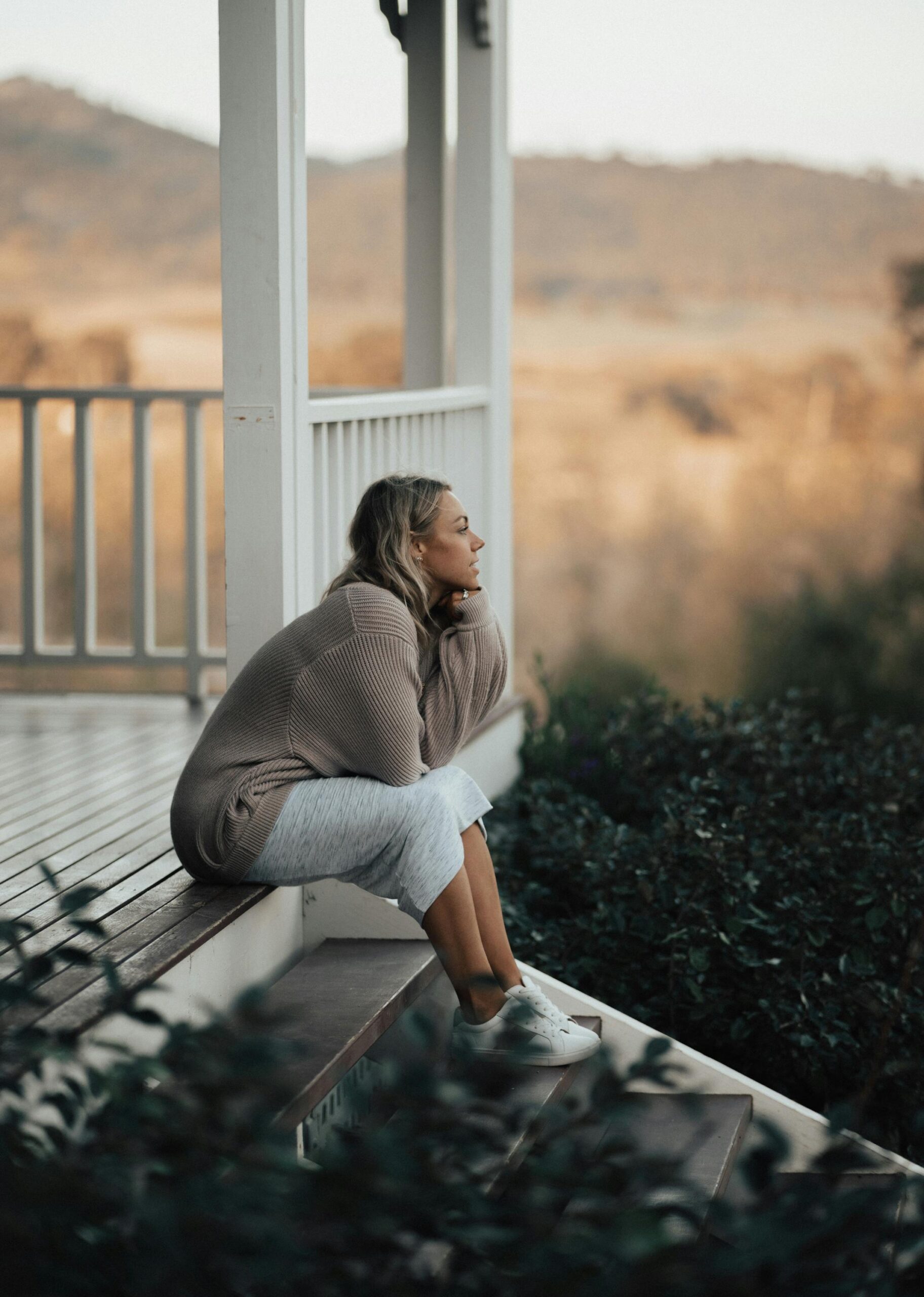 Peaceful woman sitting on a wood deck enjoying the outdoor view, with Alberta Builder Services Ltd. known as trusted garage and deck specialists.