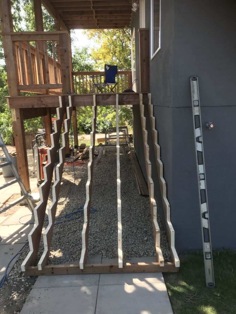 A wooden deck under construction, featuring stair framing and sturdy railings, built by Alberta Builder Services.