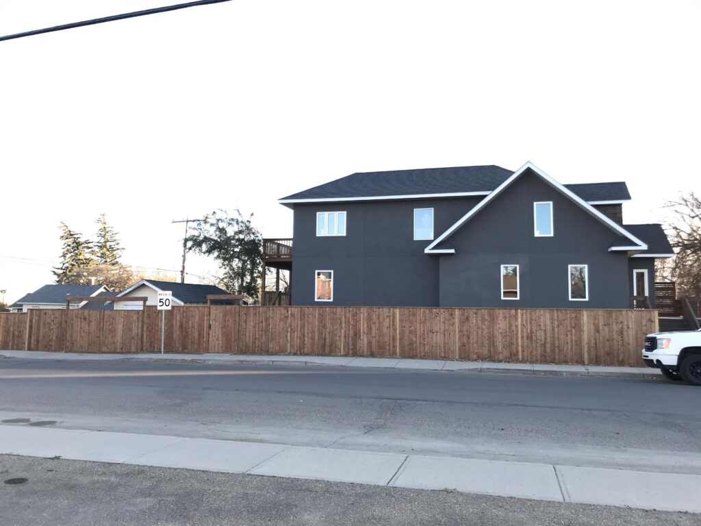 A beautifully crafted wooden fence surrounding a residential property, built by Alberta Builder Services, offering privacy and an enhanced curb appeal.