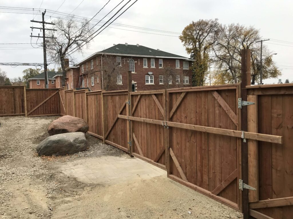 A custom-built wooden fence with dual swing gates, designed and installed by Alberta Builder Services, showcasing durability and functional craftsmanship.