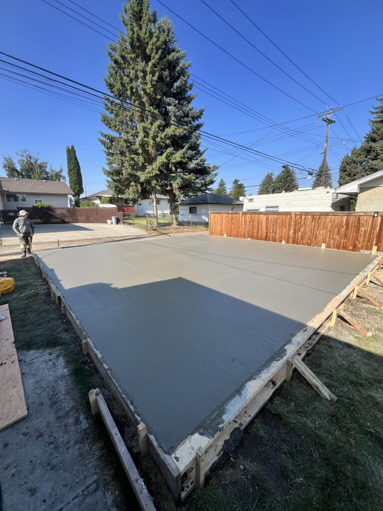 Freshly poured concrete slab for a detached garage foundation in Edmonton, showing smooth finish and formwork completed by Alberta Builder Services Ltd.