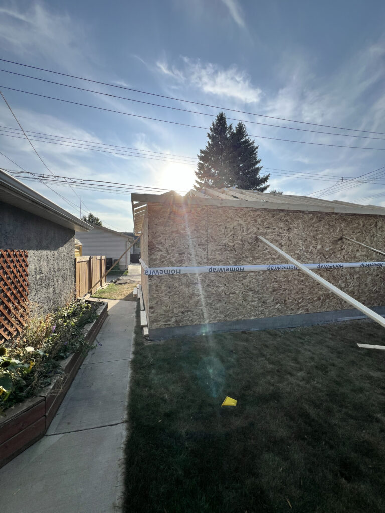 Framed detached garage in Edmonton with roof trusses installed and exterior sheathing completed by Alberta Builder Services Ltd.