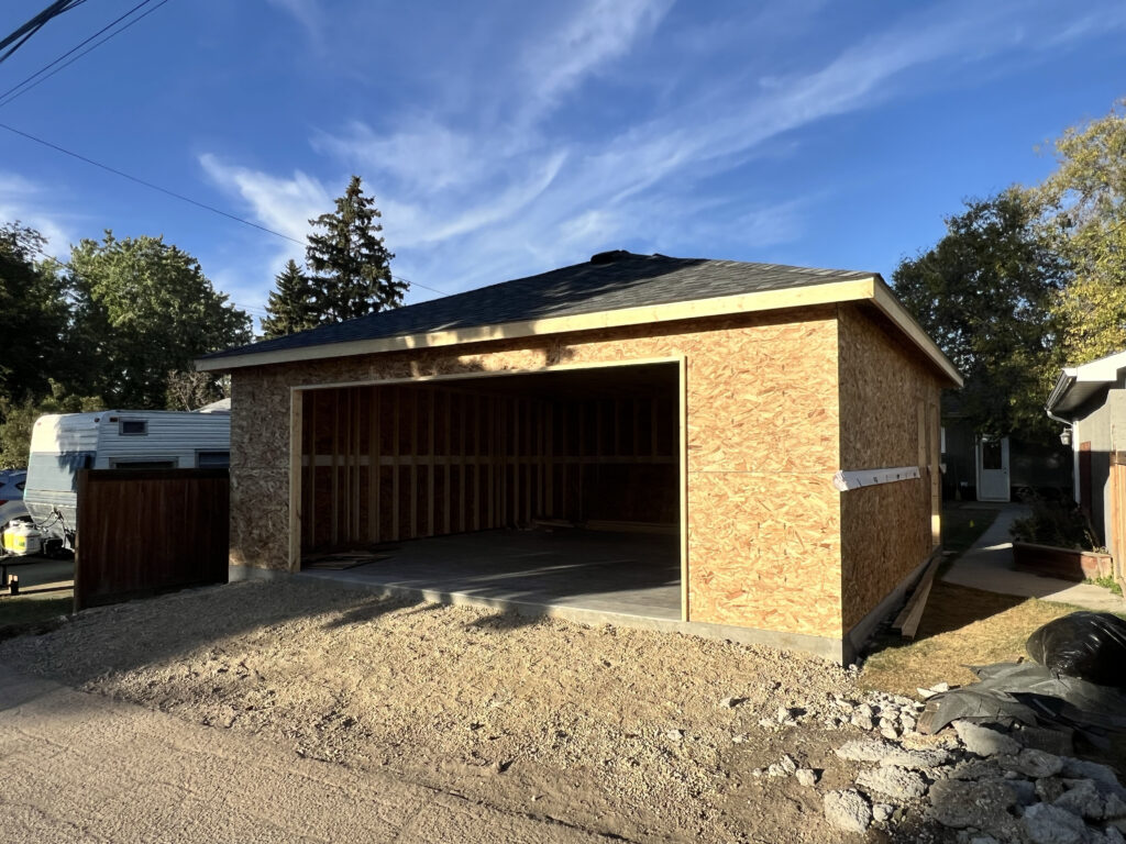 New detached garage in Edmonton with completed shingled roof and framed structure built by Alberta Builder Services Ltd.