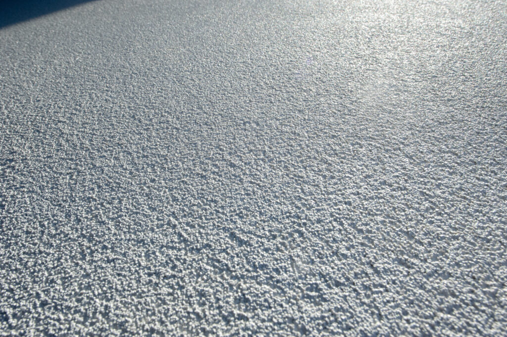 Close-up texture of Sandstorm acrylic stucco finish on an exterior wall.