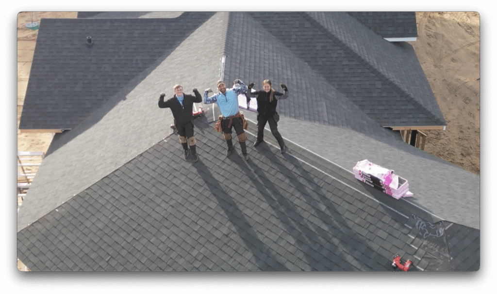 Three construction workers standing on a newly shingled roof of a residential home in Edmonton, Alberta