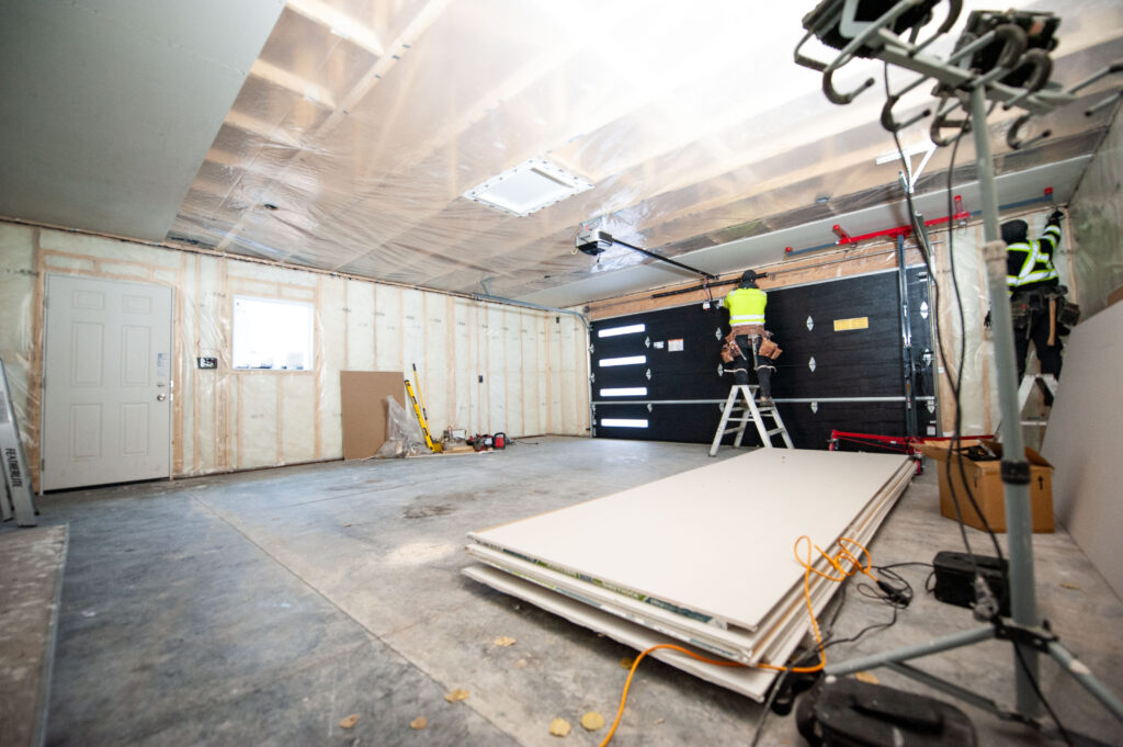Drywall installation underway in a newly insulated garage with a window and side entry door.