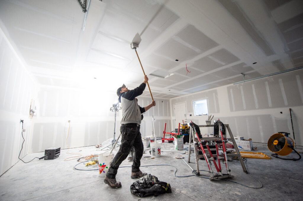 Worker applying drywall mud to the ceiling inside a newly constructed two-car garage.