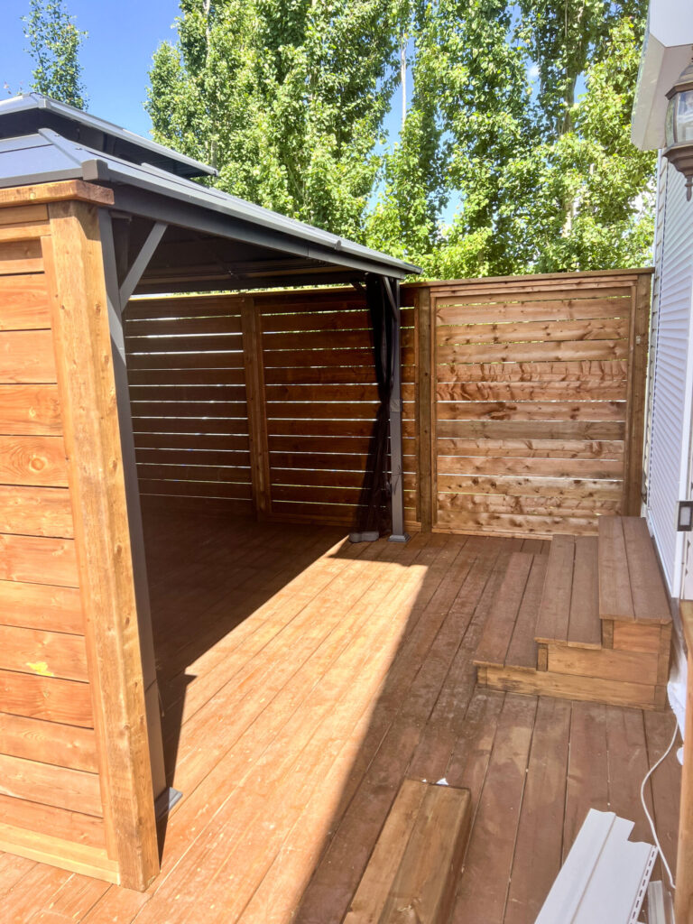 Interior view of completed deck with wood privacy walls and covered gazebo structure in Edmonton, built by Alberta Builder Services Ltd.