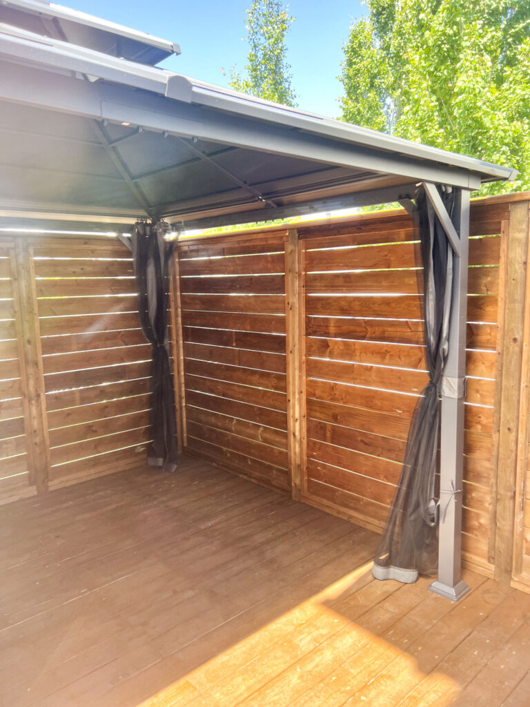 Interior view of enclosed gazebo area with wood privacy walls and metal framing on a custom deck in Edmonton, built by Alberta Builder Services Ltd.