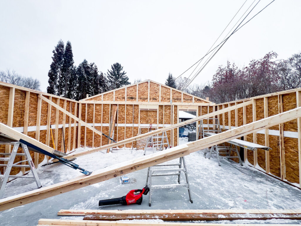 Interior garage framing in progress in Edmonton showing wall framing, gable end framing, and structural bracing during winter construction by Alberta Builder Services